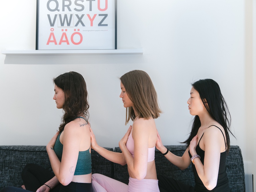 Three girls in yoga attire practicing box breathing meditation and relaxation technique